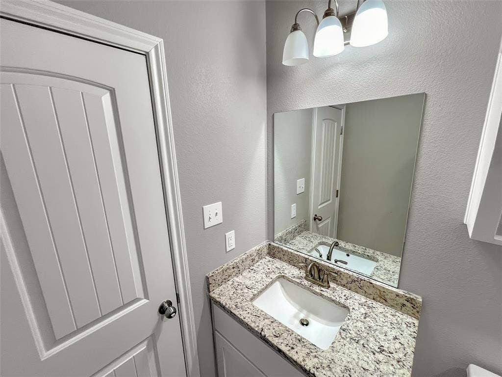 1210 Campbelton Drive, Temple, TX 76504 Bathroom vanity featuring a granite-finish countertop, under-mount sink, and brushed nickel faucet