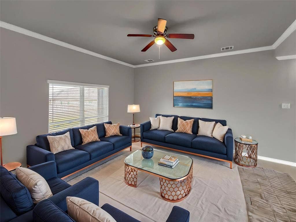 1210 Campbelton Drive, Temple, TX 76504 Virtually stagedSpacious living area featuring a ceiling fan with integrated lighting, crown molding, and a large window with horizontal blinds