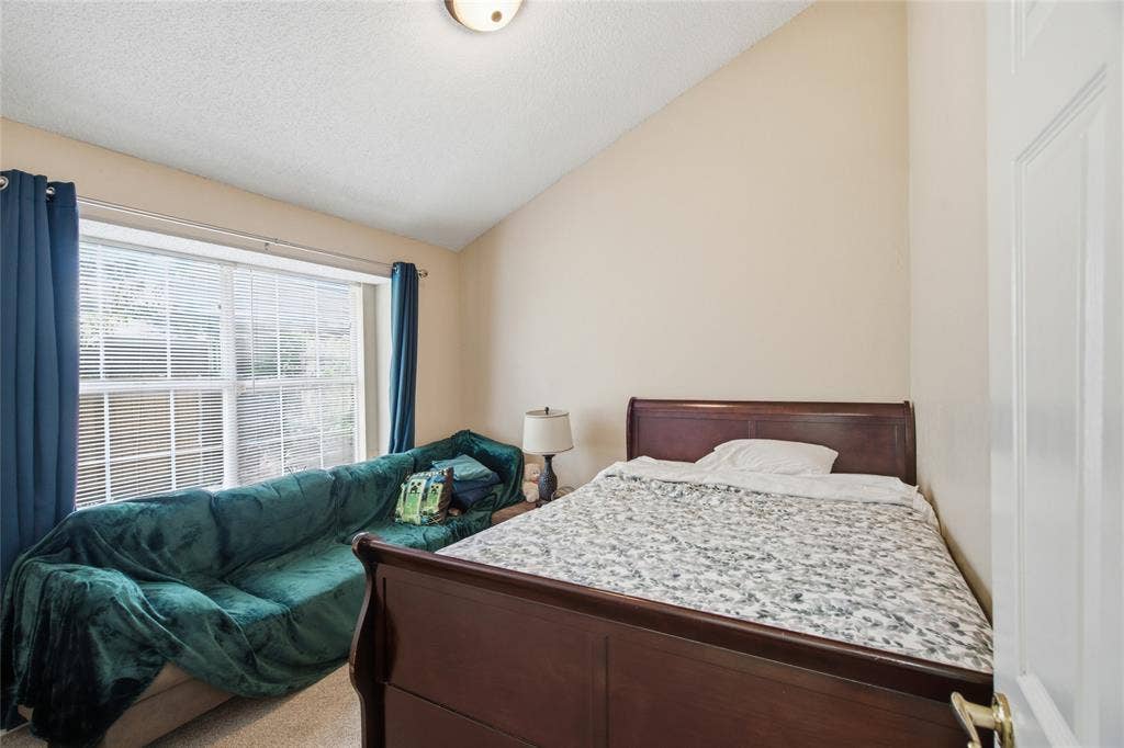 1106 Cain Court, Cedar Hill, TX 75104 Bright room featuring a large window with blinds and blue curtains, a sloped ceiling, and neutral-toned walls
