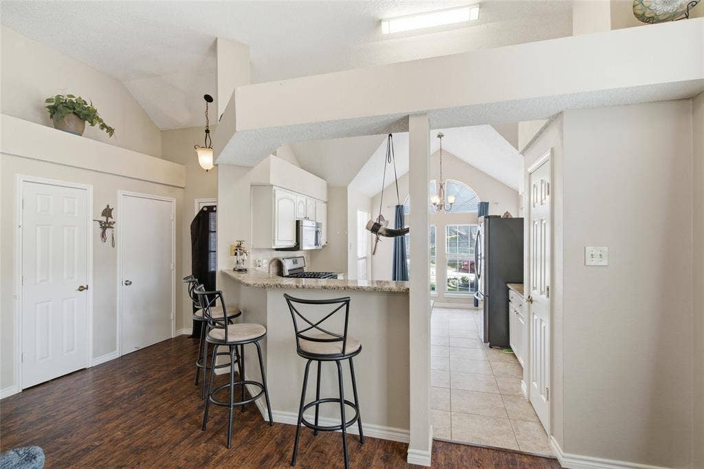 1106 Cain Court, Cedar Hill, TX 75104 Kitchen featuring a breakfast bar with stone-finish countertop, white cabinetry, and stainless steel appliances