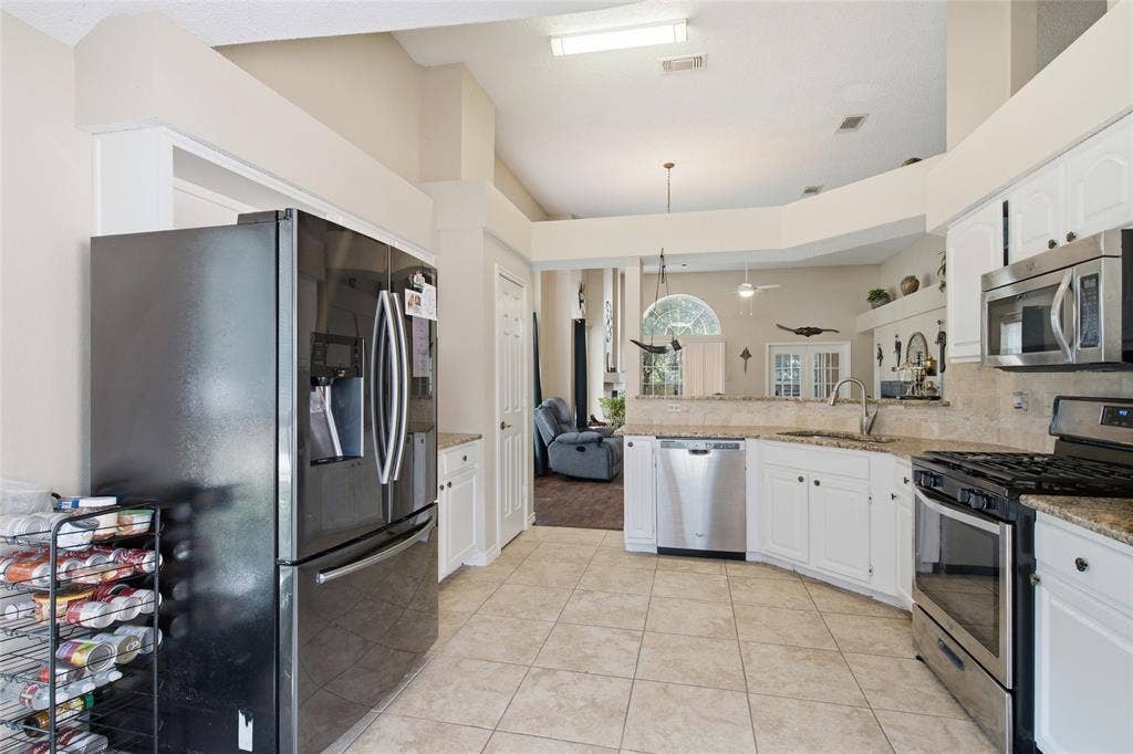 1106 Cain Court, Cedar Hill, TX 75104 Bright kitchen featuring tile flooring, white cabinetry, stainless steel appliances, a built-in dishwasher, and a curved breakfast bar