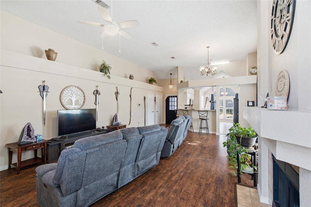 1106 Cain Court, Cedar Hill, TX 75104 Spacious living area featuring wood-finish flooring, a ceiling fan, and a fireplace with a stone hearth