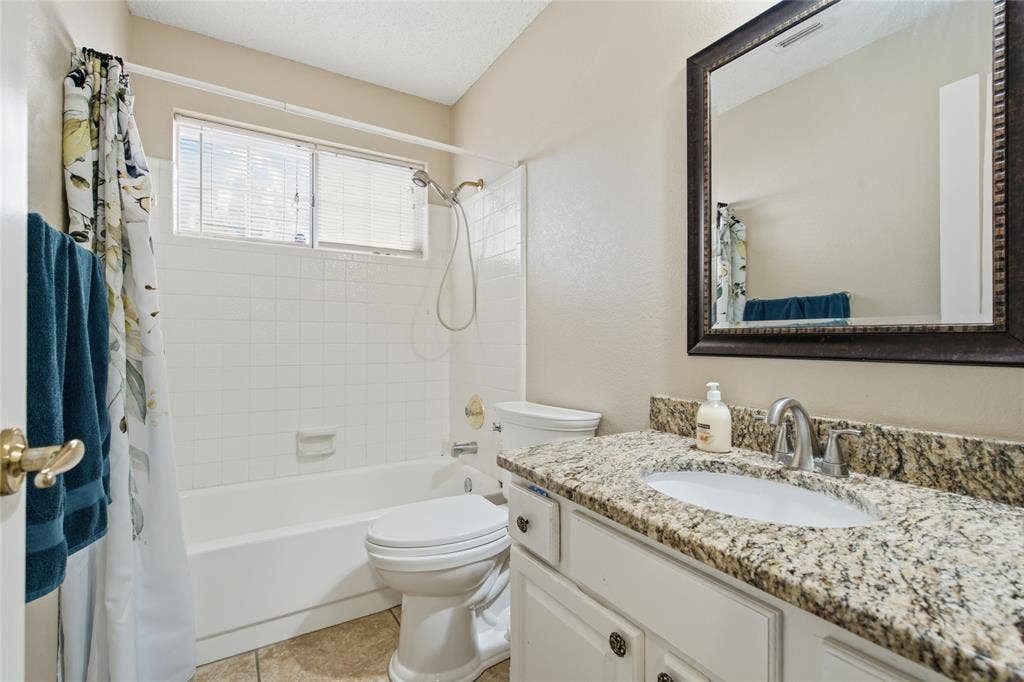1106 Cain Court, Cedar Hill, TX 75104 Bathroom featuring a white vanity with a granite-look countertop, an undermount sink, and a framed mirror