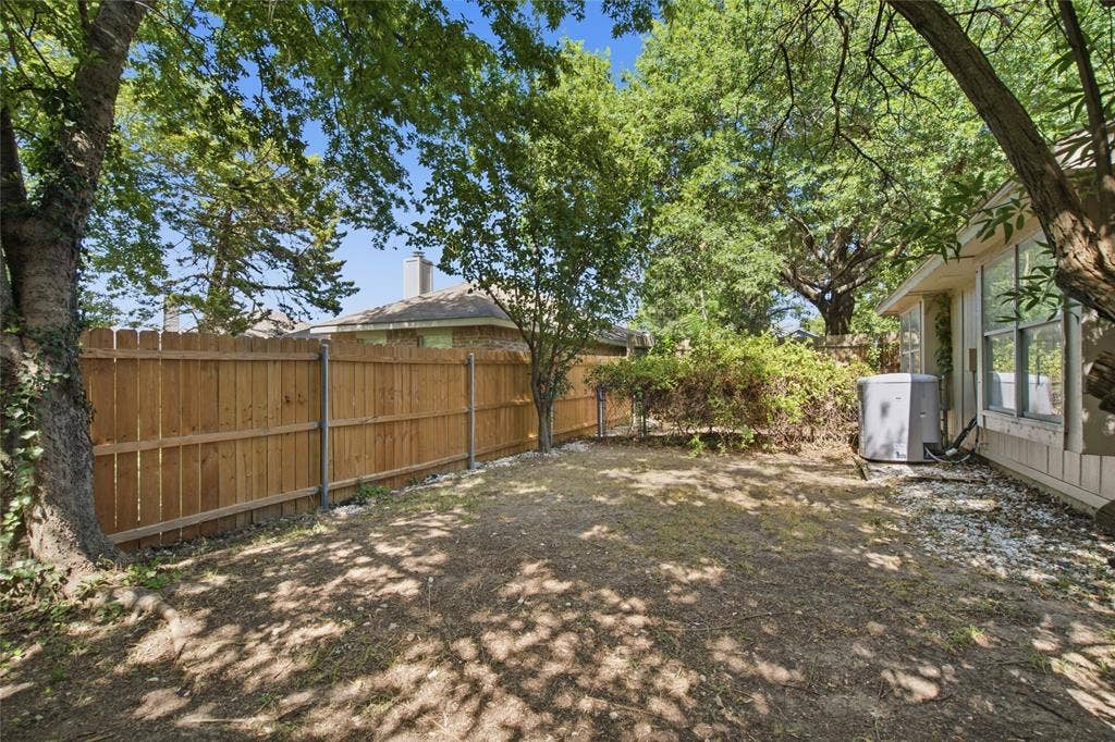 1106 Cain Court, Cedar Hill, TX 75104 Private backyard space featuring a wood privacy fence, mature trees, and a gravel perimeter alongside the property
