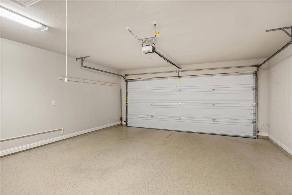 2038 Clive Drive, Granbury, TX 76048 Spacious garage featuring an epoxy coated floor, overhead lighting, and an automatic garage door opener