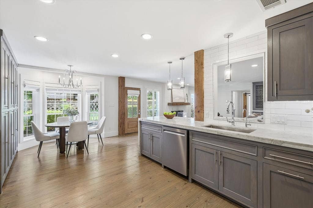 4310 Forest Bend Road, Dallas, TX 75244 Kitchen featuring a spacious island with a built-in sink, gray cabinetry, stainless steel appliances, and a white subway tile backsplash