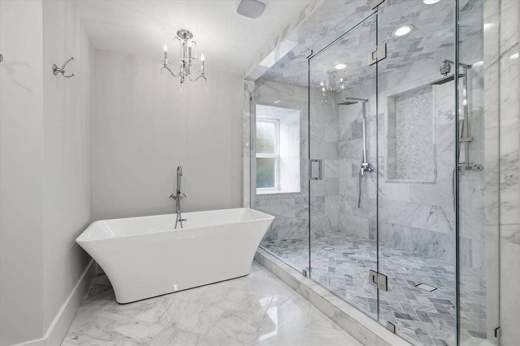 4310 Forest Bend Road, Dallas, TX 75244 Freestanding soaking tub with floor-mounted faucet, frameless glass shower enclosure, double shower heads, and marble tile flooring