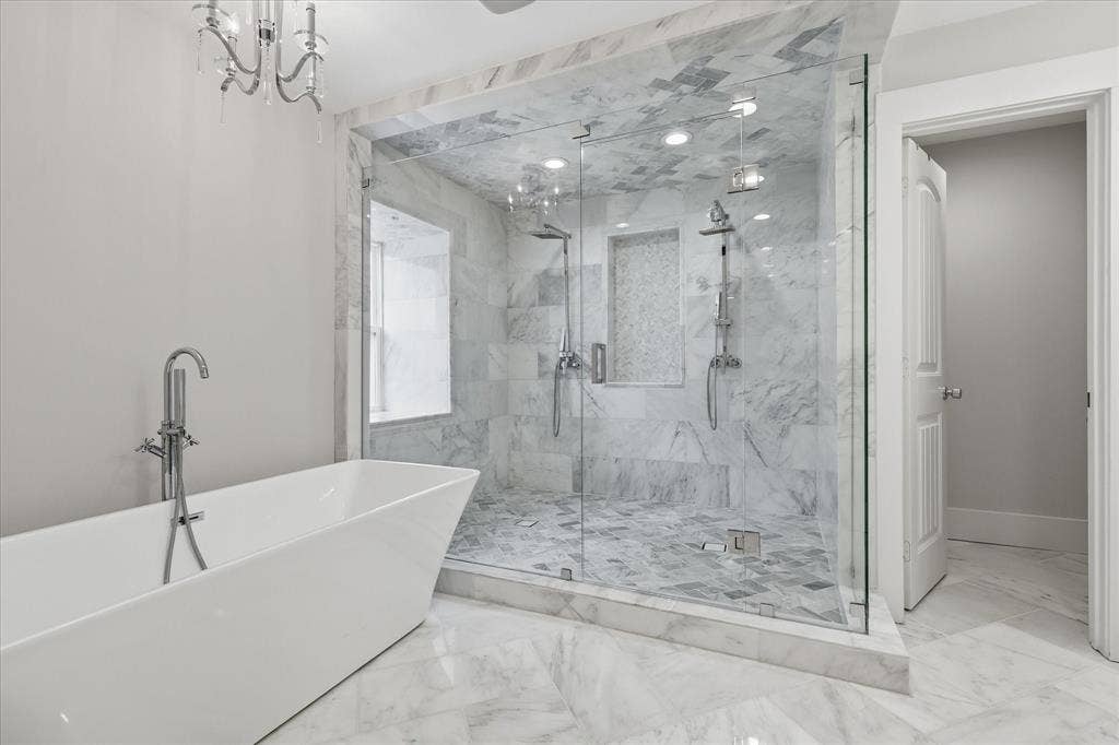 4310 Forest Bend Road, Dallas, TX 75244 Freestanding soaking tub with floor-mounted faucet, expansive glass-enclosed shower featuring dual shower heads, and marble-finish tile flooring