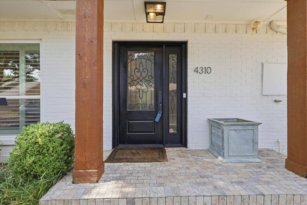 4310 Forest Bend Road, Dallas, TX 75244 White brick exterior with a black entry door featuring decorative glass and a sidelight
