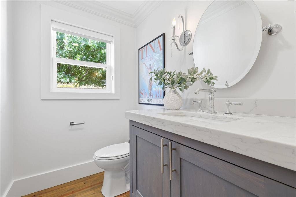 4310 Forest Bend Road, Dallas, TX 75244 Powder room featuring a single-sink vanity with a quartz countertop, chrome fixtures, and a wall-mounted oval mirror
