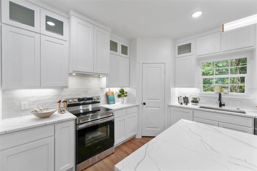 117 Parkside Drive, Trinidad, TX 75163 Kitchen featuring extensive white cabinetry, light-toned countertops, tile backsplash, stainless steel range, and wood-finish flooring