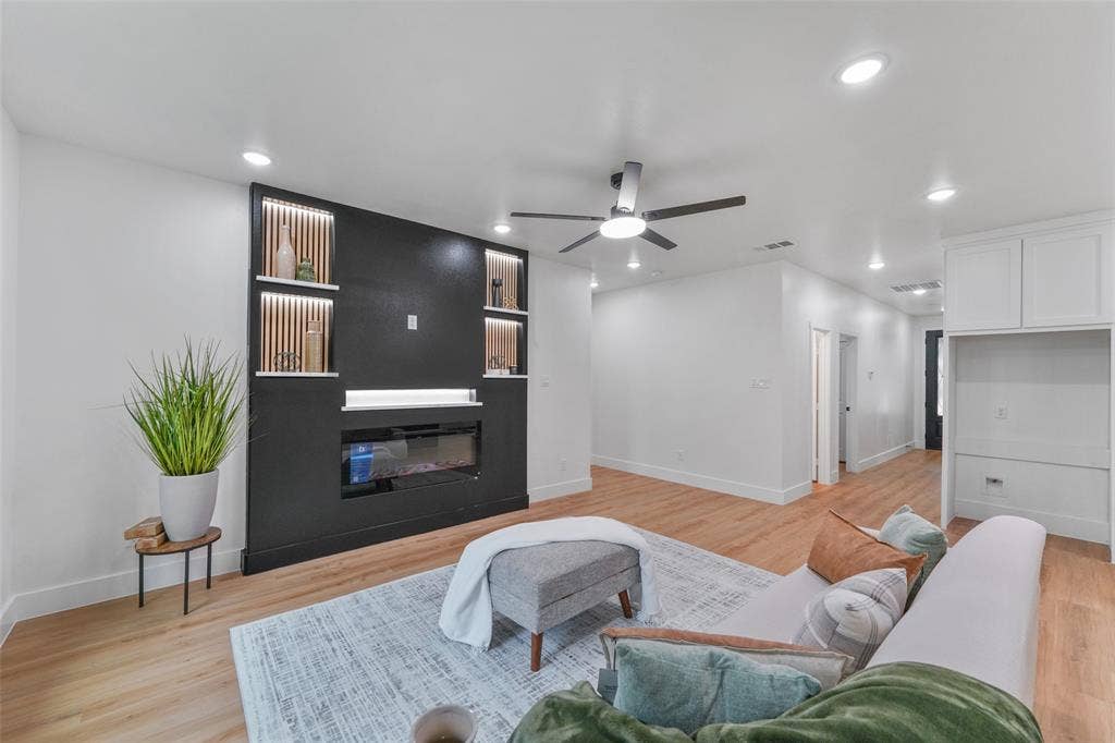 117 Parkside Drive, Trinidad, TX 75163 Living area featuring a contemporary dark accent wall with an electric fireplace, integrated shelving with accent lighting, and wood-finish flooring