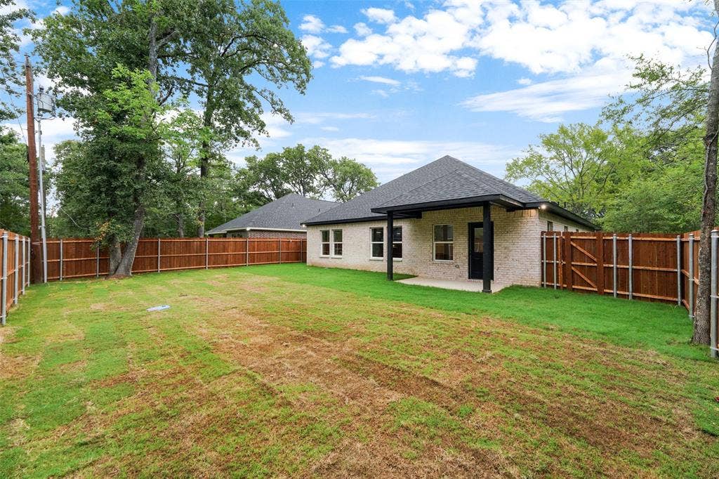 117 Parkside Drive, Trinidad, TX 75163 Expansive backyard featuring a new wood privacy fence, a covered patio, and a light brick exterior