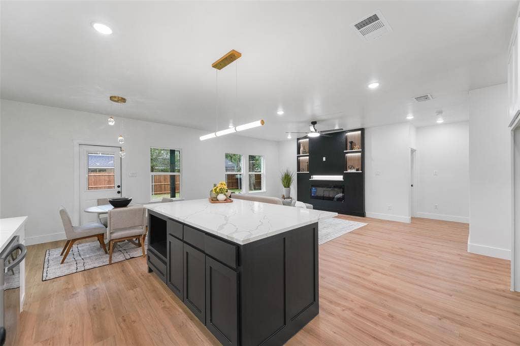 117 Parkside Drive, Trinidad, TX 75163 Open-concept living space featuring a substantial kitchen island with a light-toned countertop, wood-finish flooring, recessed lighting, and a built-in media center with shelving and an electric fireplace