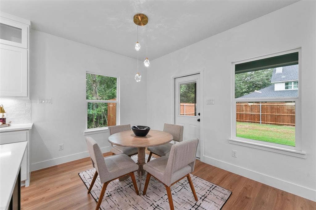 117 Parkside Drive, Trinidad, TX 75163 Dining area featuring wood-finish flooring, a contemporary three-light pendant fixture, and white cabinetry with a quartz countertop and subway tile backsplash