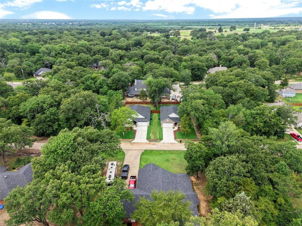 117 Parkside Drive, Trinidad, TX 75163 Aerial view of a residential neighborhood featuring several single-story homes with dark shingle roofs, surrounded by extensive mature tree coverage