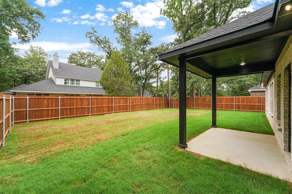 117 Parkside Drive, Trinidad, TX 75163 Expansive backyard featuring a new wood privacy fence, a covered patio with recessed lighting, and a brick exterior with multiple windows