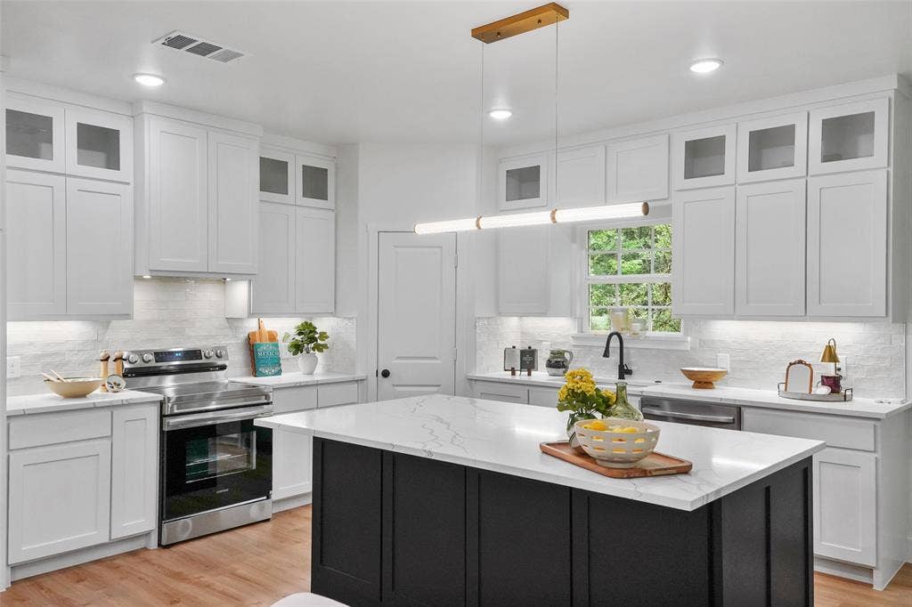 117 Parkside Drive, Trinidad, TX 75163 Gourmet kitchen featuring a large central island with a quartz countertop, white shaker cabinetry with some glass-front uppers, stainless steel appliances, and wood-finish flooring