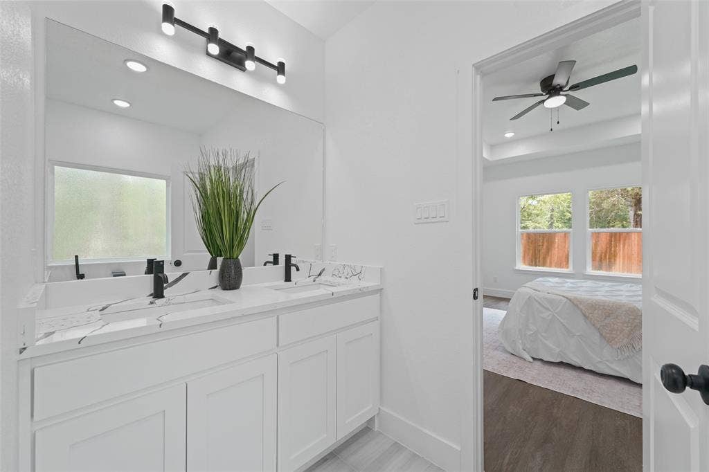 122 E Beachwood Loop, Trinidad, TX 75163 Bathroom vanity featuring a dual sink with matte black fixtures, a single large mirror, white cabinetry, and a window with frosted glass