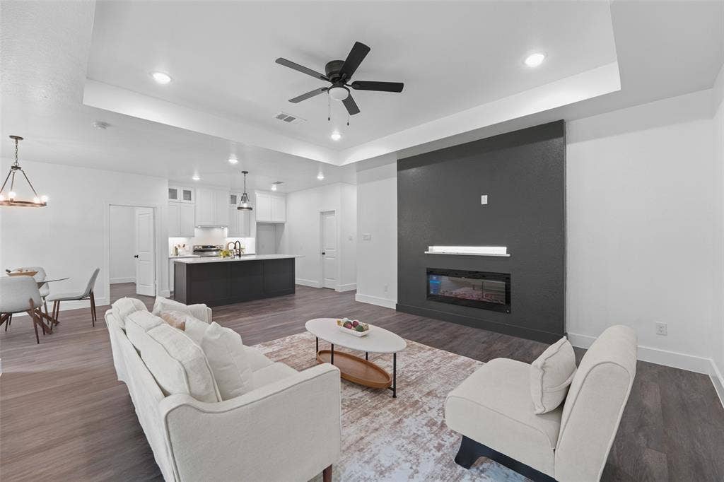122 E Beachwood Loop, Trinidad, TX 75163 Open-concept living space featuring wood-finish flooring, a contemporary dark accent wall with an integrated electric fireplace, and recessed lighting