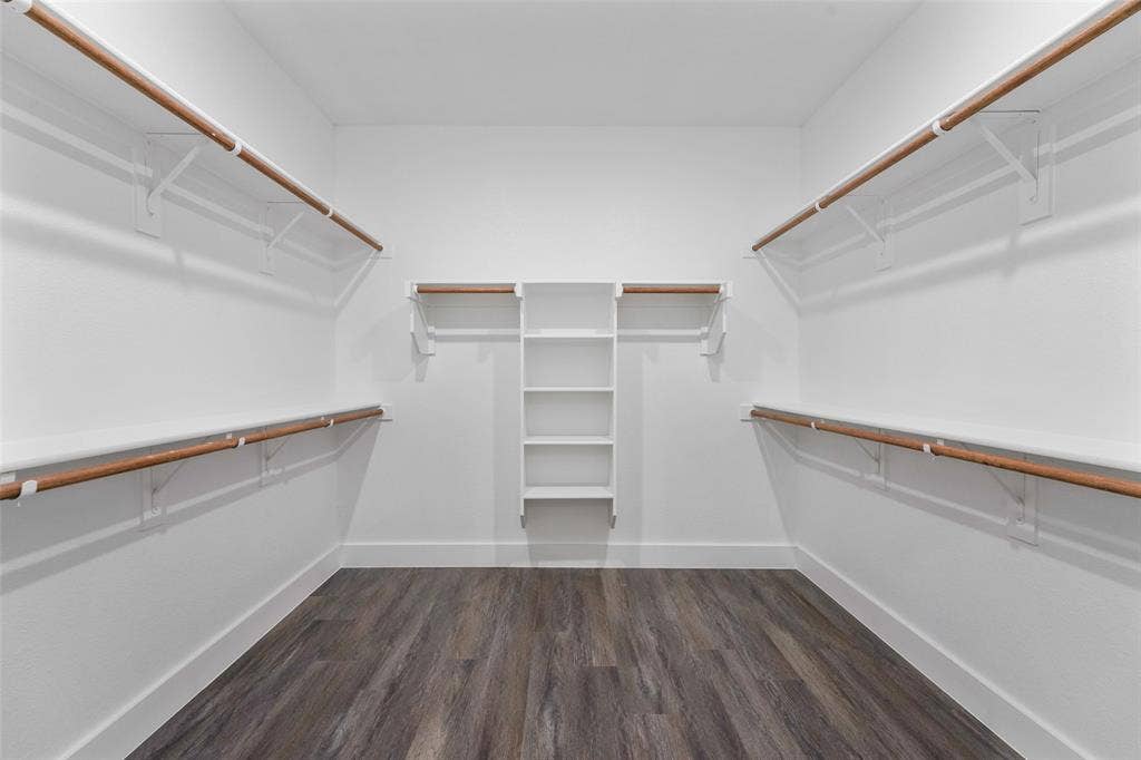122 E Beachwood Loop, Trinidad, TX 75163 Spacious walk-in closet featuring wood-finish flooring, white walls, built-in shelving, and multiple clothing rods