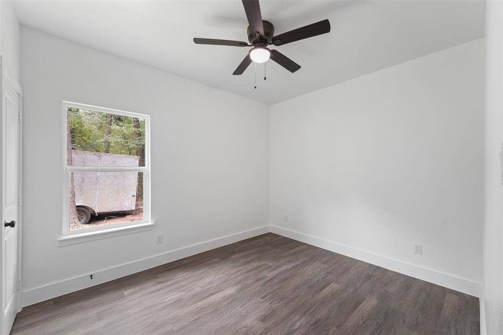 122 E Beachwood Loop, Trinidad, TX 75163 Bright interior space featuring a window with exterior views, wood-finish flooring, white walls, and a ceiling fan with integrated lighting
