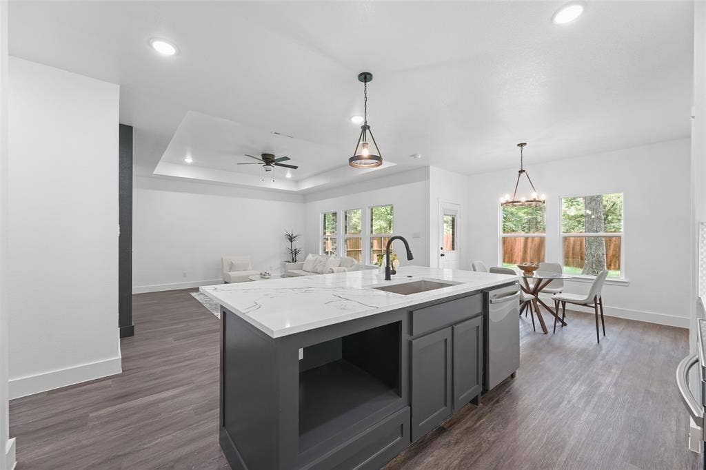 122 E Beachwood Loop, Trinidad, TX 75163 Open-concept living space featuring a central kitchen island with a quartz countertop and integrated sink, pendant lighting, wood-finish flooring, and ample natural light from multiple windows