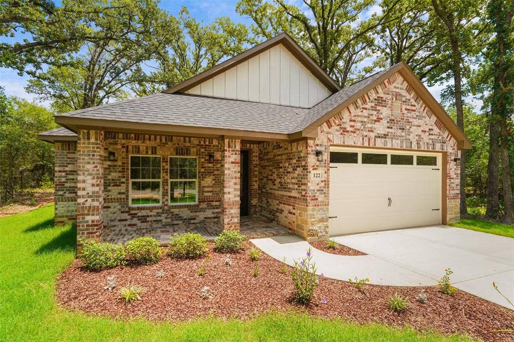122 E Beachwood Loop, Trinidad, TX 75163 Brick and siding exterior featuring a covered front porch, an attached garage with decorative hardware, a concrete driveway, and established landscaping