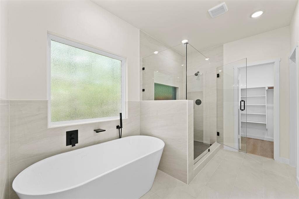 231 E Beachwood Loop, Trinidad, TX 75163 Contemporary bathroom featuring a freestanding soaking tub with matte black fixtures, a spacious walk-in shower with glass enclosure, large format tile flooring, and recessed lighting
