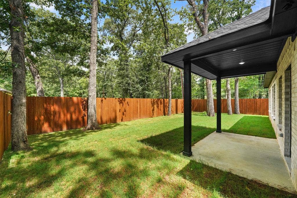 231 E Beachwood Loop, Trinidad, TX 75163 Expansive backyard featuring a covered patio, concrete slab, brick exterior, full wood privacy fence, and mature trees