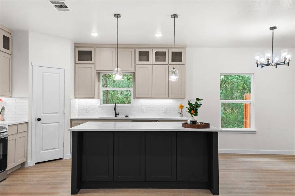 231 E Beachwood Loop, Trinidad, TX 75163 Modern kitchen featuring a central island with a light-toned countertop, a matte black kitchen faucet, light wood-finish flooring, and pendant lighting fixtures