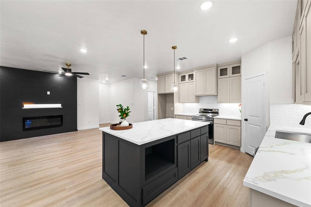 231 E Beachwood Loop, Trinidad, TX 75163 Open-concept living space featuring a central kitchen island with a white countertop, two pendant lights, and light wood-finish flooring throughout