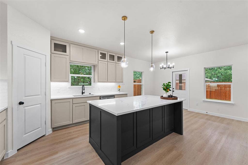 231 E Beachwood Loop, Trinidad, TX 75163 Open-concept kitchen featuring an oversized island with a white surface, contrasting dark cabinetry, wood-finish flooring, and pendant lighting