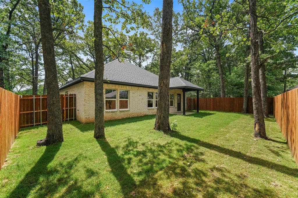 231 E Beachwood Loop, Trinidad, TX 75163 Expansive green lawn framed by mature trees and a privacy fence