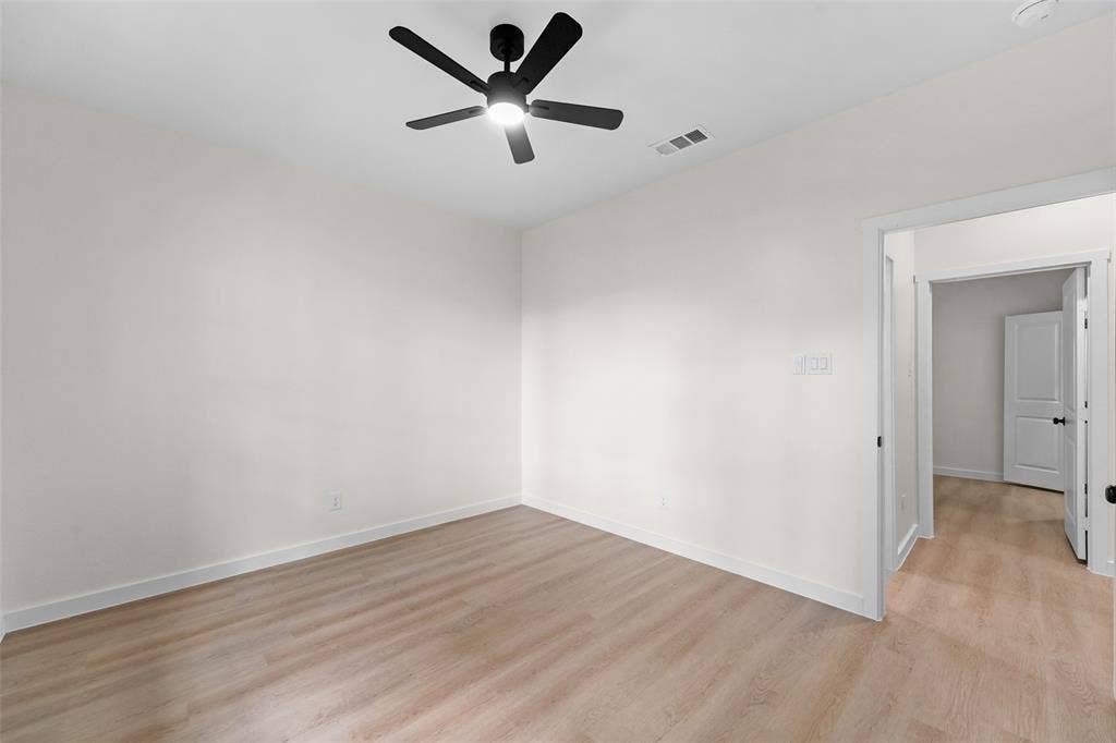 231 E Beachwood Loop, Trinidad, TX 75163 Spacious room featuring wood-finish flooring, white baseboards, and a modern black ceiling fan with integrated lighting