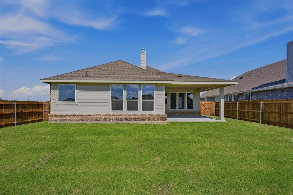 Expansive backyard featuring a covered patio, a brick and siding exterior, and a privacy fence