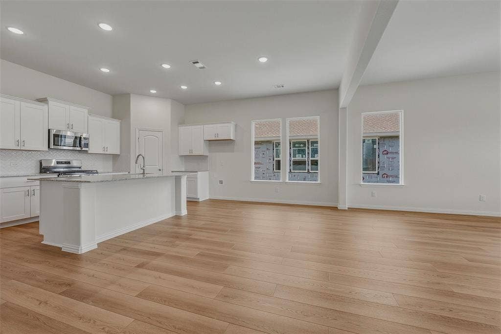Open-concept living space featuring wood-finish flooring, recessed lighting, and multiple windows