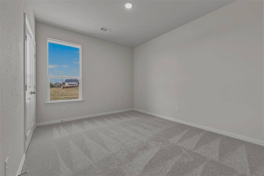 Neutral wall paint, gray carpeting, and a window with a white frame