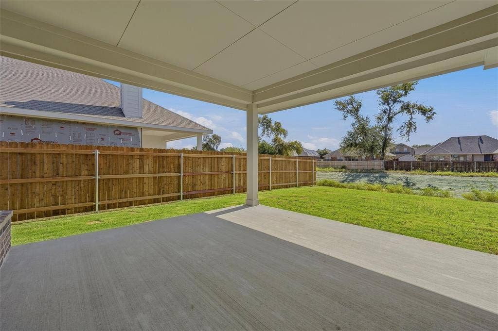 Covered patio with a concrete surface, expansive lawn, and wood privacy fencing