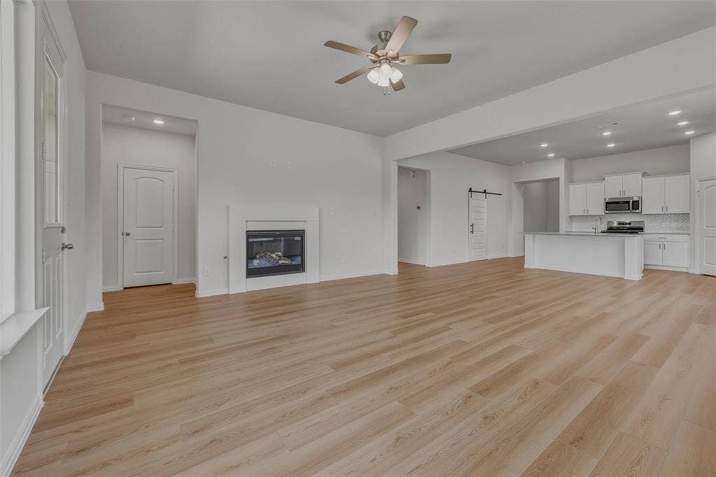 Spacious open-concept living area featuring wood-finish flooring, a contemporary fireplace, and an integrated kitchen with an island