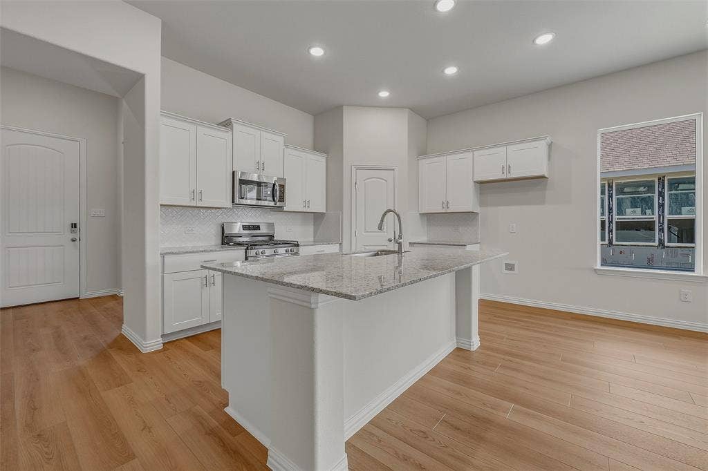 Kitchen featuring a central island with countertop, shaker-style cabinetry, wood-finish flooring, recessed lighting, and stainless steel appliances