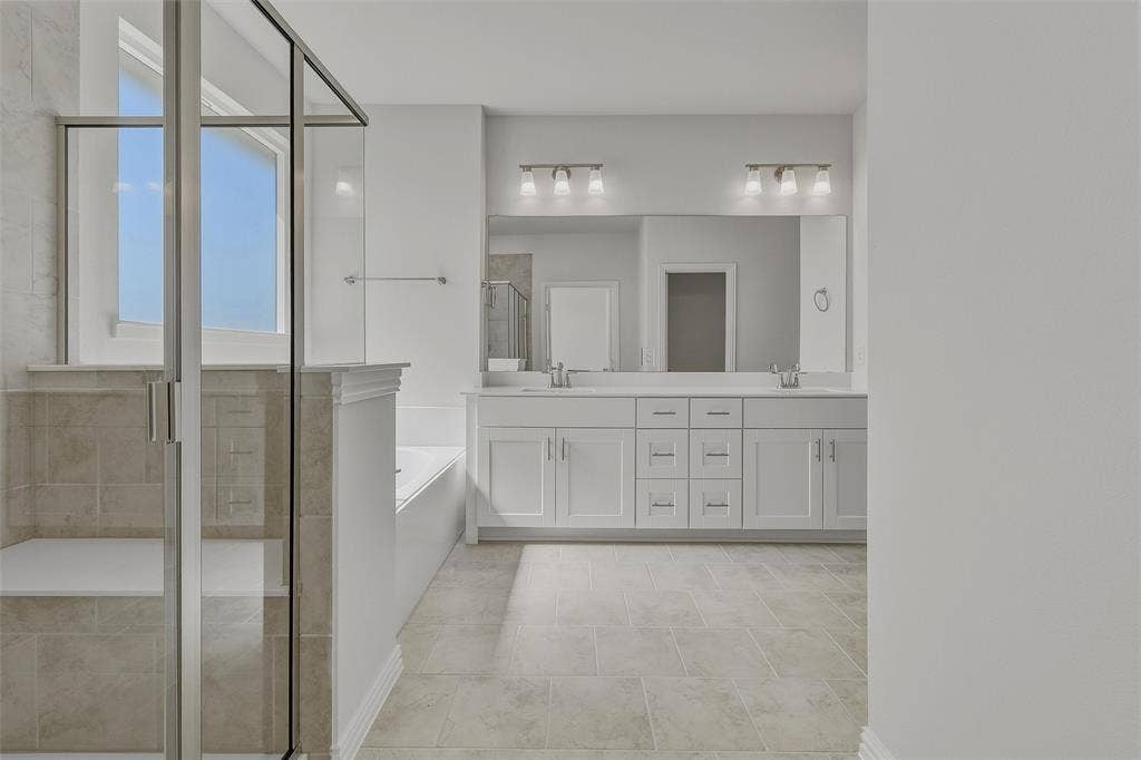 Frameless glass shower enclosure with built-in bench, soaking tub, dual vanity with undermount sinks, and tile flooring