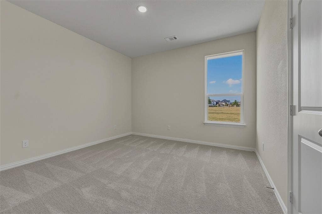 Neutral wall color, recessed ceiling lighting, light-toned carpeting, and a window with outdoor scenery