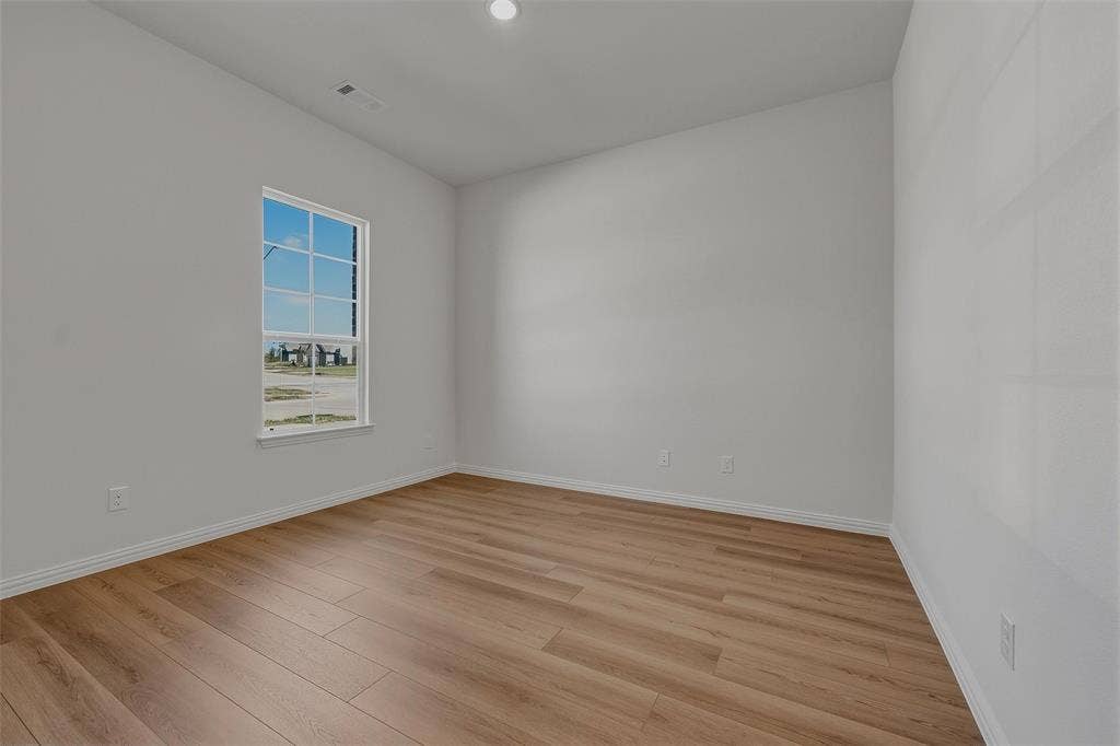 Wood-finish flooring, white baseboards, and a single window with grids