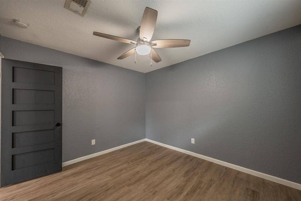 5612 Macgregor Drive, Haltom City, TX 76148 Interior room featuring wood-finish flooring, gray walls, white baseboards, and a contemporary ceiling fan with integrated lighting
