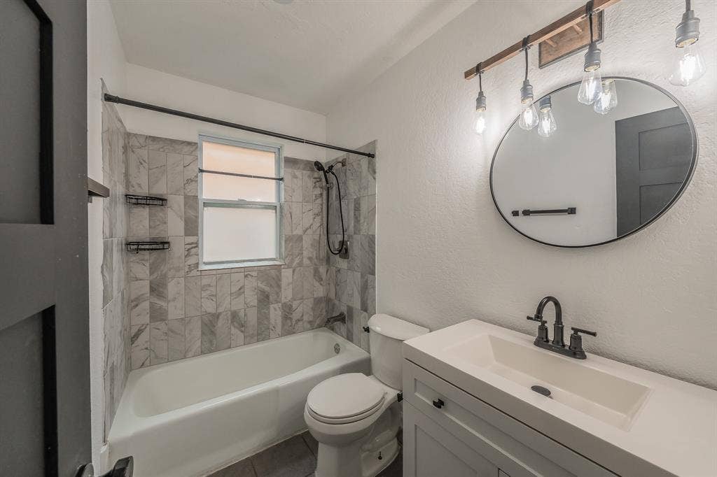 5612 Macgregor Drive, Haltom City, TX 76148 Bathroom featuring a white vanity with integrated sink, black-finish faucet, and coordinating oval mirror