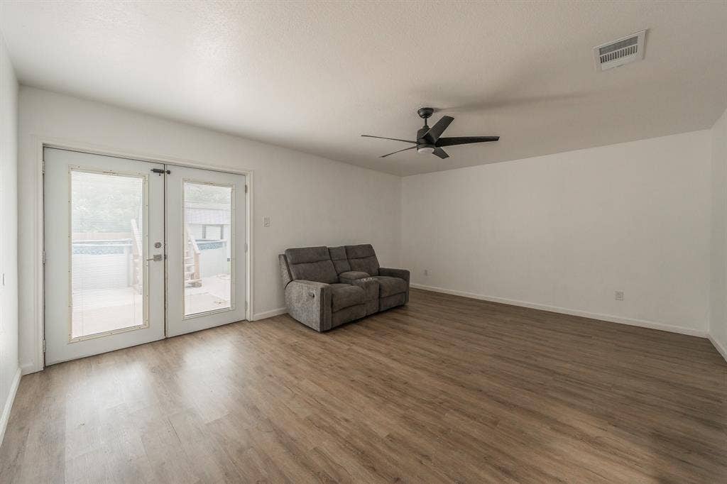 5612 Macgregor Drive, Haltom City, TX 76148 Spacious room featuring wood-finish flooring, crisp white walls, and a contemporary black ceiling fan