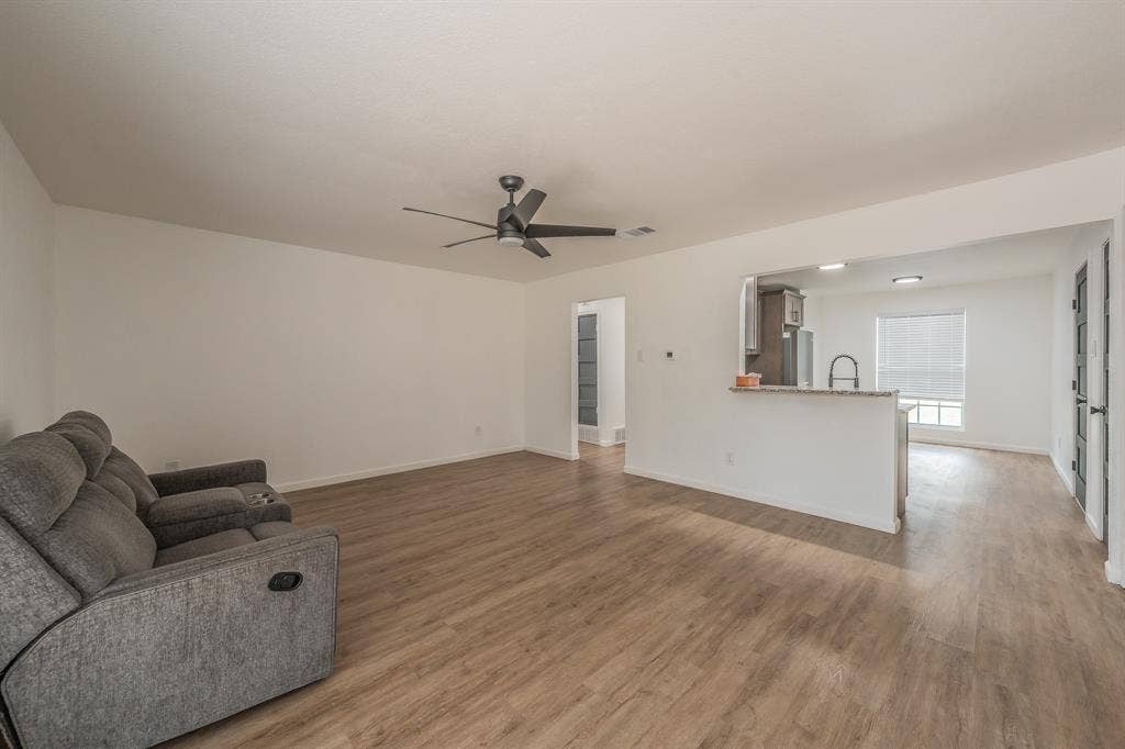 5612 Macgregor Drive, Haltom City, TX 76148 Open-concept living space featuring wood-finish flooring, a contemporary ceiling fan, and white walls