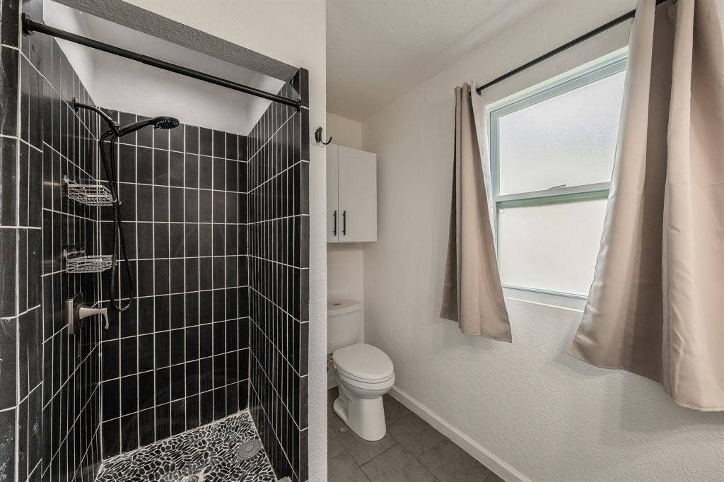 5612 Macgregor Drive, Haltom City, TX 76148 Shower with vertical black tile surround and pebble flooring