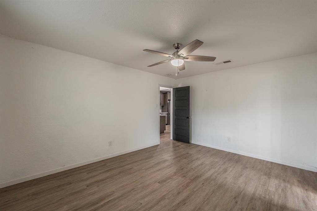 5612 Macgregor Drive, Haltom City, TX 76148 Spacious room with wood-finish flooring, white walls, and a ceiling fan with light fixture